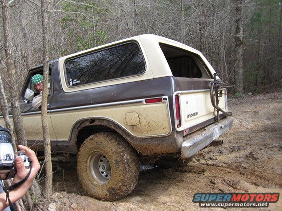 Tan and brown 1978 Ford Bronco rear view, off-roading in mud