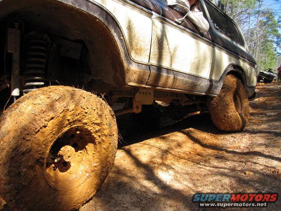 Mud-covered 1978 Ford Bronco side view, off-roading on a dirt trail
