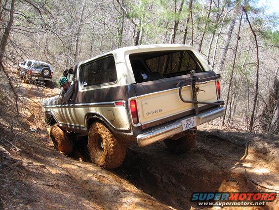 1978 Ford Bronco with mud tires climbing a steep dirt hill, another SUV behind it