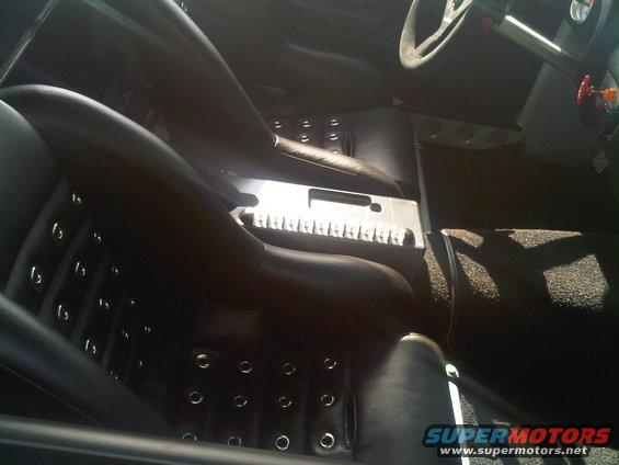 Black leather bucket seats with grommets, metal center console, and steering wheel