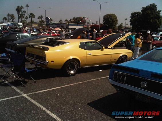 Yellow 1971 Ford Mustang Mach 1 with hood open, parked at a car show