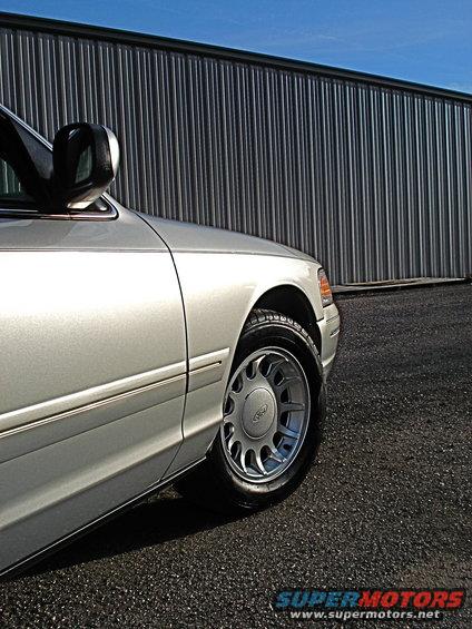 Silver 2000 Ford Crown Victoria 3/4 front view showing wheel and side panel