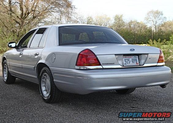 Silver 2000 Ford Crown Victoria sedan, rear 3/4 view, parked on gravel