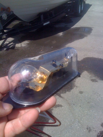 Boat trailer light assembly with clear plastic cover and bulb held in hand