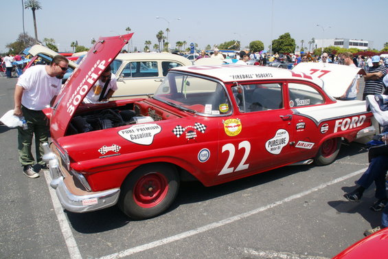 Red and white Ford race car with number 22 and "Fireball Roberts" on roof. Hood is open, showing engine. Two people looking at engine