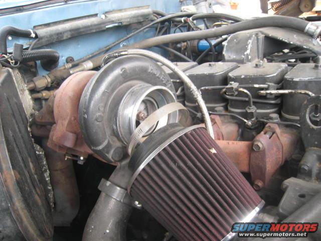 Close-up of a turbocharger and air filter attached to an engine block with visible fuel lines