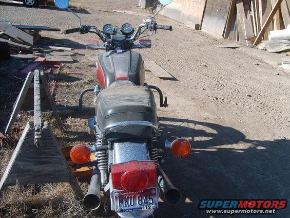 Motorcycle rear view with license plate MKU 845. Wood debris and construction materials in background