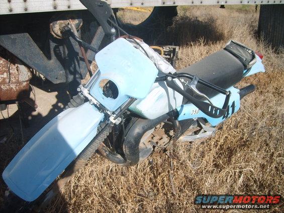 Light blue dirt bike with number 41 on the side, parked on dry grass next to a trailer