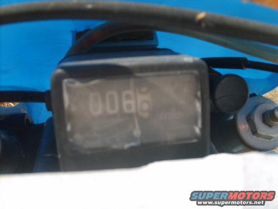 Motorcycle dashboard with digital odometer showing 0066, blue plastic fairing, and black handlebars
