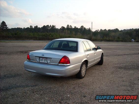 Silver 2003 Ford Crown Victoria parked on a gravel lot, rear view