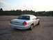 2003 Ford Crown Victoria - A silver 2003 Ford Crown Victoria is seen from the rear on a gravel lot with trees in the background.