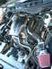 2003 Ford Crown Victoria - Engine bay view shows a V8 engine with aftermarket air intake and red filter. A badge with a horse emblem is present on the engine cover.