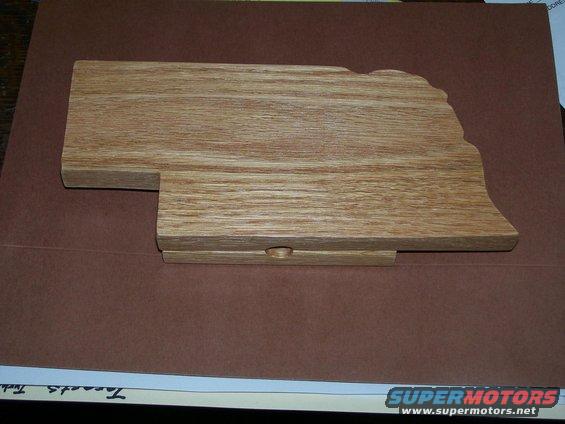 Wooden shape of Nebraska on a brown surface with some papers underneath