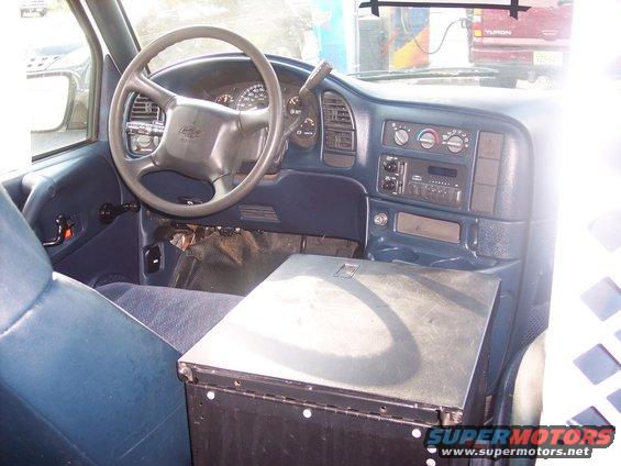 Interior shot of a van or truck dashboard and seats. Shows steering wheel, radio, and center console