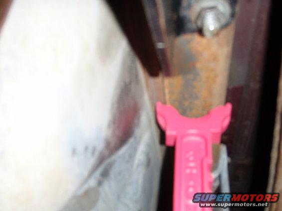 Close-up of a pink suspension component near rusty metal