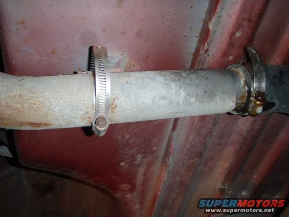 Exhaust pipe secured with hose clamp, red undercarriage visible