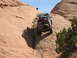 1986 Ford Bronco II - An off-road vehicle navigates a challenging rocky terrain under a clear blue sky.
