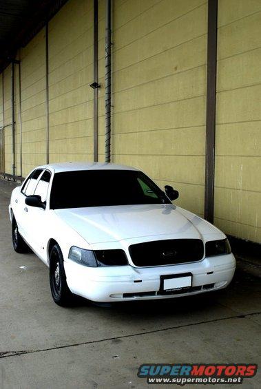 White 1998 Ford Crown Victoria parked on concrete, front 3/4 view, black grille, tinted headlights