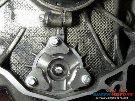Close-up of engine component with three bolts securing a metal plate