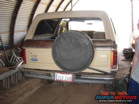 Rear view of a tan and brown Ford Bronco with a spare tire mounted on the back. License plate reads 3SB Z68