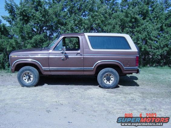 Brown Ford Bronco with a white top, parked outside