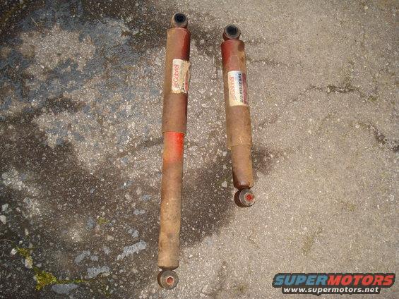 Two Gabriel shock absorbers with red bands on a concrete surface