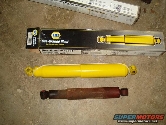 Two shock absorbers, one new yellow NAPA Gas-Grande Fleet and one old rusty red shock absorber