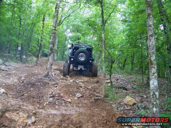 Off-road vehicle climbing a muddy hill in a forest