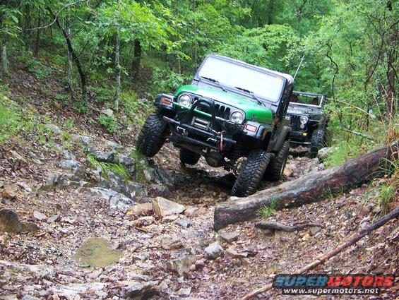 Green Jeep Wrangler navigating a difficult rocky trail with another Jeep behind it