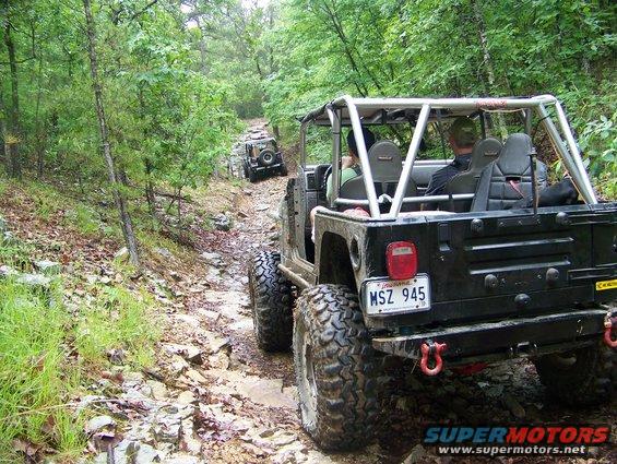 Rear view of black Jeep Wrangler with license plate MSZ 945 on a rocky trail, following another Jeep