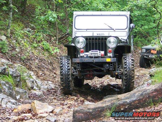 Jeep truck on rocky trail, another Jeep behind it