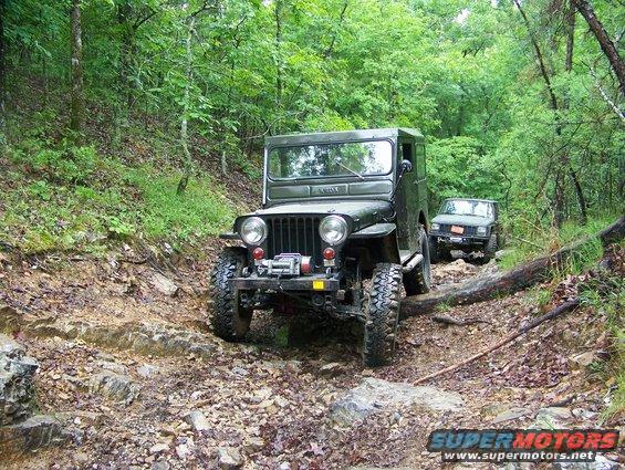 Olive green Jeep with winch on rocky trail, another Jeep behind