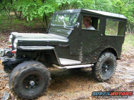 olive green Jeep CJ-5 driving on a rocky trail