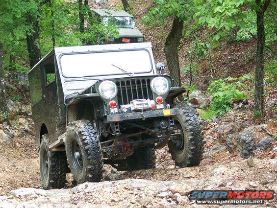 Old Jeep on a rocky trail with another vehicle behind it in the woods