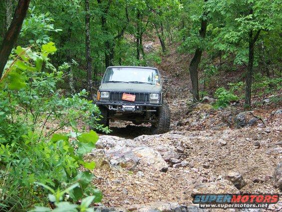 Green Jeep Cherokee navigating a rocky off-road trail