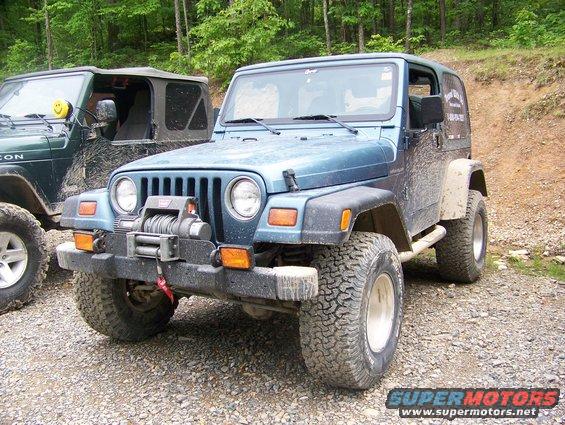 Blue Jeep Wrangler TJ with winch on front bumper, parked next to a green Jeep