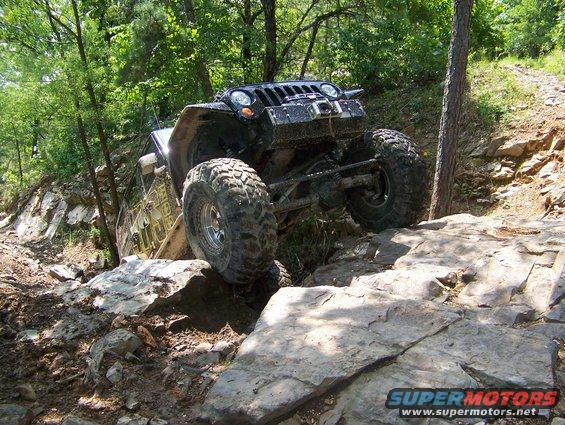 Black Jeep Wrangler with large tires on a rocky trail