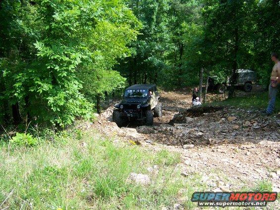 Black Jeep Wrangler on a rocky trail, 4wd.com sticker on windshield