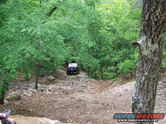 Black off-road vehicle on rocky trail in wooded area