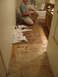 1983 Ford 427 - A man is installing new floor tiles in a bathroom, with the old flooring exposed.