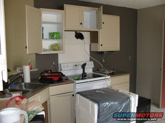 Kitchen scene with cabinets, sink, stove, and covered appliance