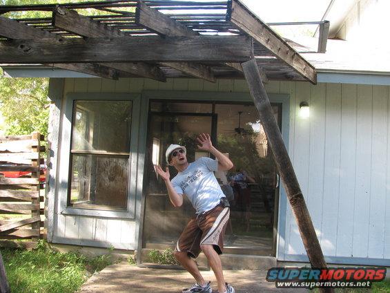 guy in hard hat and sunglasses making a scared face under a wooden pergola that looks like it's about to fall