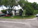 1983 Ford 427 - A red sports car and a green pickup truck are parked in the driveway of a suburban house on a sunny day.