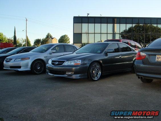 Dark gray sedan with chrome rims parked in a lot, front 3/4 view