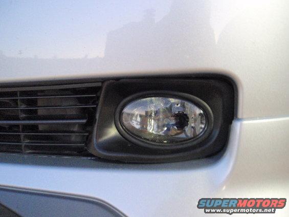 Close-up of a car's front fog light and part of the grille. Watermark says SUPERMOTORS.NET
