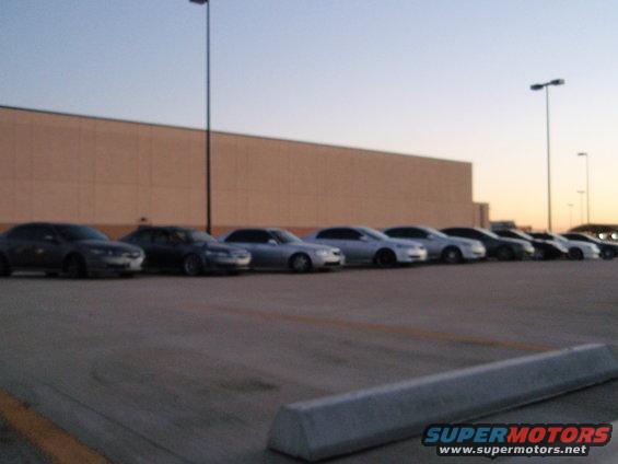 Several sedans parked in a row in front of a large building