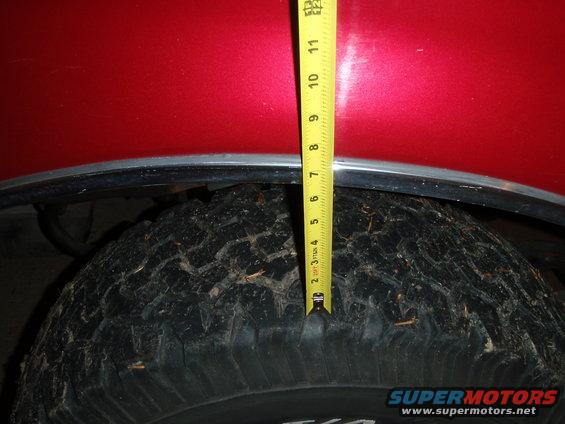 Red vehicle fender over tire, tape measure showing 7 inches of clearance