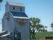 1994 Ford Bronco - A weathered grain elevator stands tall against a clear blue sky, with a logo indicating it's a Montana Elevator.