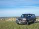 1994 Ford Bronco - A 1994 Ford Bronco sits on a hill overlooking a vast, arid landscape under a clear blue sky.