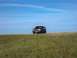 1994 Ford Bronco - Dark SUV drives on a grassy hill under a clear blue sky.